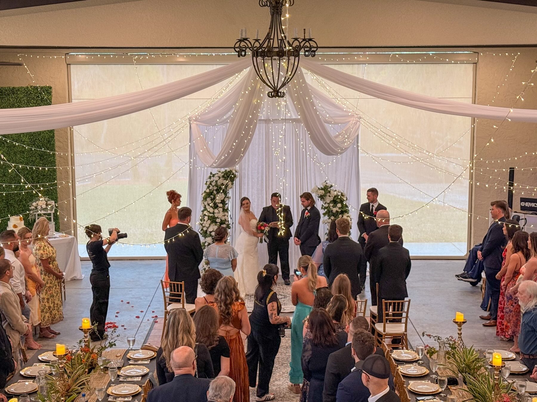 Covered ceremony with draping and string lights at Bonita Ranch wedding venue in Melbourne Florida with guests seated at reception tables