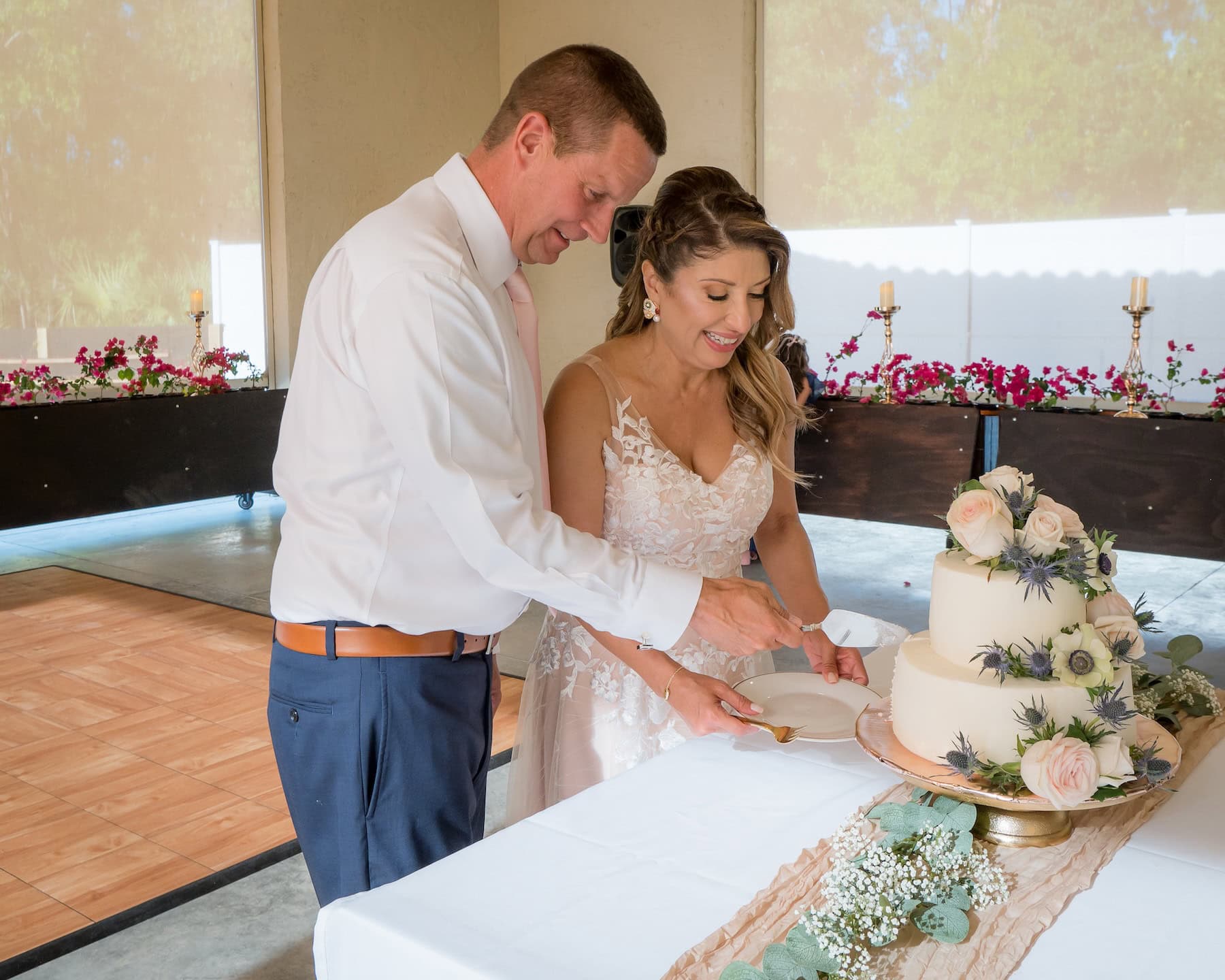 Couple cutting wedding cake during elopement at Bonita Ranch with bougainvillea plant decor in Melbourne Florida