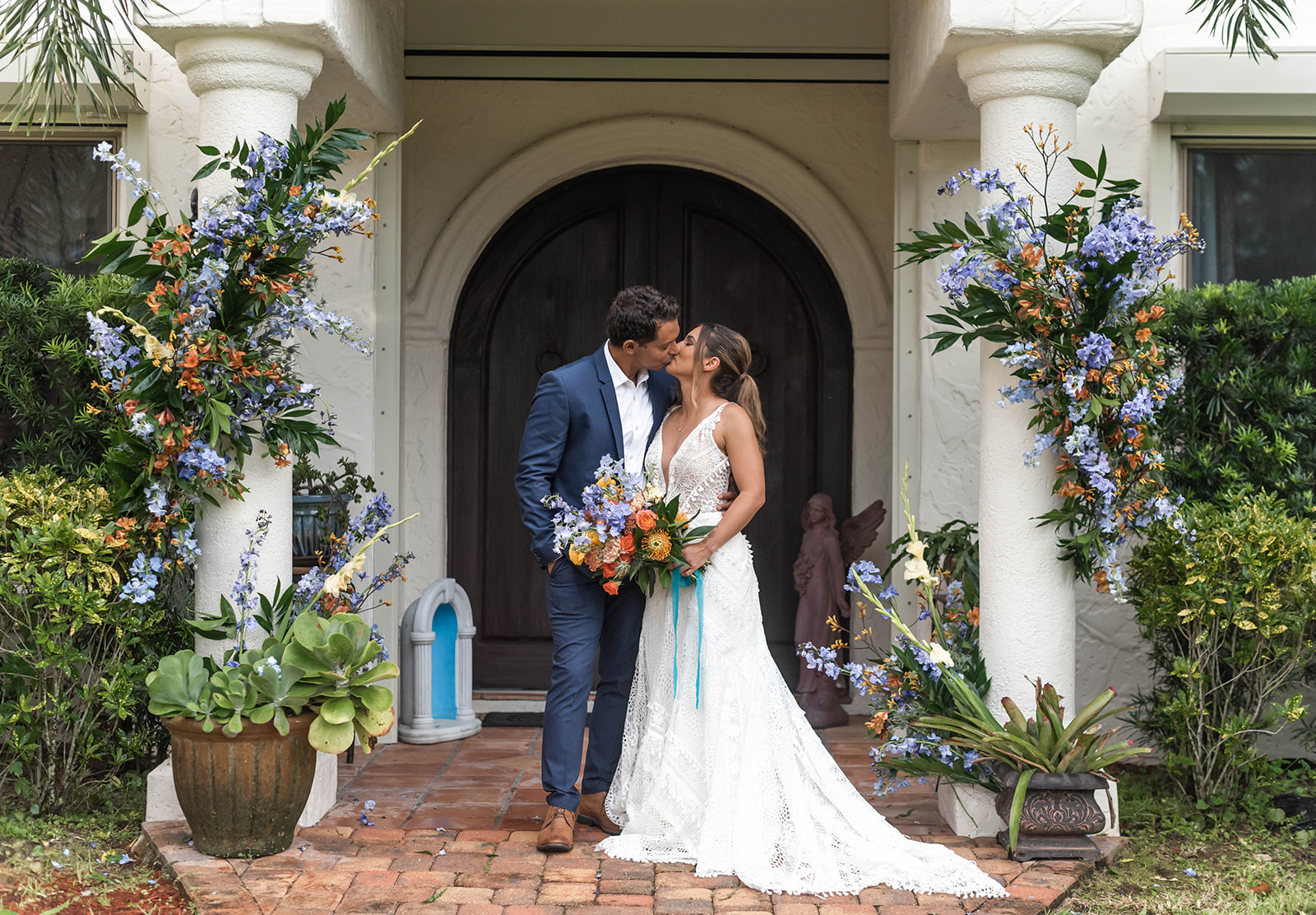 Bride and groom kissing at garden ceremony entrance with floral decor at Bonita Ranch wedding venue in Melbourne Florida