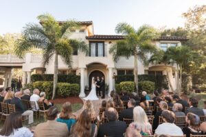 Outdoor wedding ceremony at Bonita Ranch, a Mediterranean-style wedding venue in Melbourne, Florida with guests seated in front of the villa during a romantic ceremony. Photo by Winship Photography