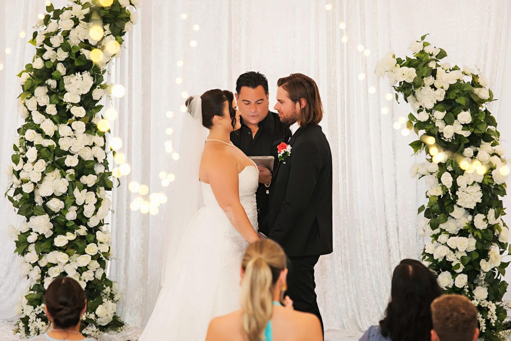 Rain backup wedding ceremony at Bonita Ranch in Melbourne Florida with couple exchanging vows under covered floral arch