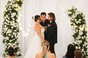 Rain backup wedding ceremony at Bonita Ranch in Melbourne Florida with couple exchanging vows under covered floral arch