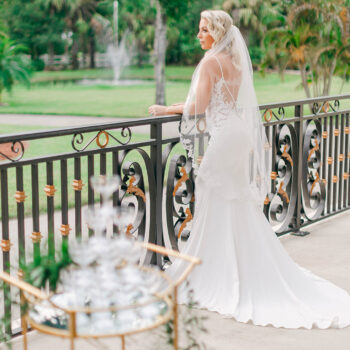 A bride gazing at the beautiful grounds of Bonita Ranch from the Montecarlo balcony, featuring elegant French railing in Melbourne, Florida.